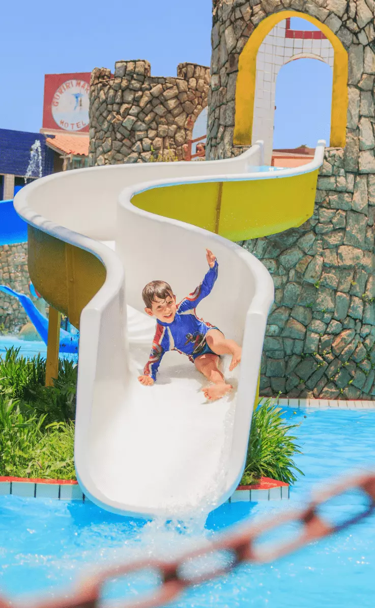 Menino descendo o escorregador do Playground Infantil